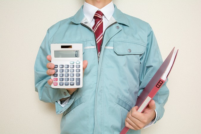 作業服姿で電卓を持つ人